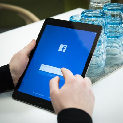 Mies kahvilassa kirjautumassa Facebookiin iPadilla.