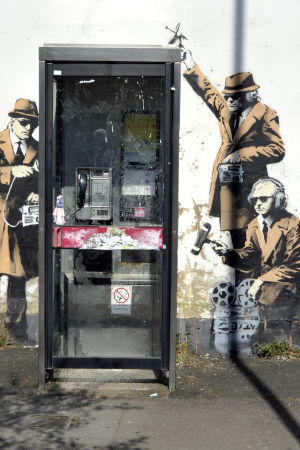 Underrättelseagenter avlyssnar en telefonkiosk i Cheltenham i Storbritannien. Banksys konstverk i Cheltenham, Storbritannien.