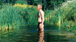 Veijo Rönkkönen seisoo ammessa uimahousuihin pukeutuneena.