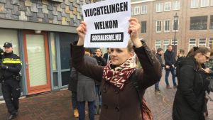 Leneke håller upp ett plakat där hon önskar flyktingar välkomna. Ung holländsk kvinna håller upp plakat där hon önskar flyktingar välkomna i staden Spijkenisse där den högerpopulistiska kandidaten Geert Wilders inledde sin valkampanj den 18 februari 2017.