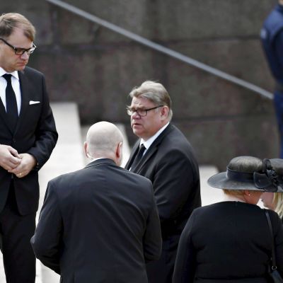 Turvamies seuraa vierestä, kun pääministeri Juha Sipilä ja ulkoministeri Timo Soini saapuvat siunaustilaisuuteen Tuomiokirkkoon presidentti Mauno Koiviston valtiollisissa hautajaisissa Helsingissä 25. toukokuuta 2017.