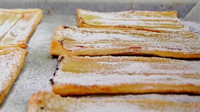 En bakplåt med nybakade rabarberpajer. Pajerna är bakade på smördegsplattor med tunnt hyvlade rabarberstjälkar och ett ordentligt lager med pudrat florsocker.