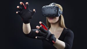 Vissa tillverkare har utvecklat ett par handskar som ska förstärka upplevelsen av den virtuella verkligheten. En kvinna med virtuella glasögon och ett par virtuella handskar.