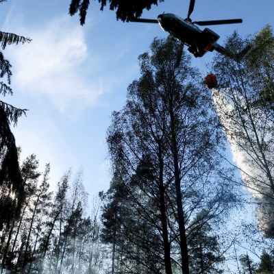Rajavartiolaitoksen helikopteri auttamassa sammutustöissä pudottamalla 2000 litran sammutuspussilla vettä maastoon Nurmijärvellä 17. toukokuuta.