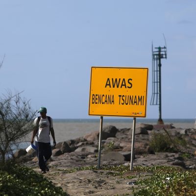 Mies ohitti tsunamivaroituskyltin Banda Acehissa 21. joulukuuta 2019.