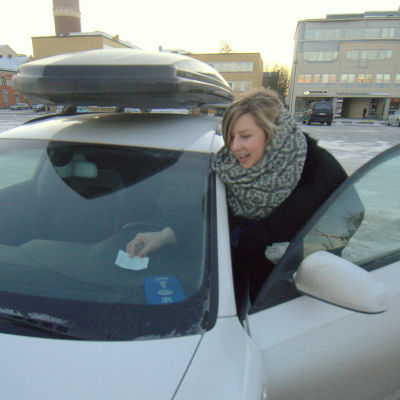 Elin Mäenpää placerar parkeringsbeviset i bilen på Maria Malm-tomten i Jakobstad.