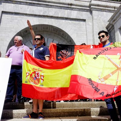 Miehiä iskulauseiden ja Espanjan lipun kanssa, taustalla henkilö tekee fasistitervehdystä.