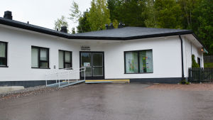 Hälsostationen i Forsby borde bevaras, anser både Daniel Hannus (SDP) och Roger Turku (SFP). Ett vitt hus med svart tak. Ovanför dörren finns en skylt där det står hälsogård terveystalo.