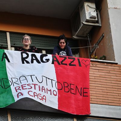 Kuvassa italialaiset oleskelevat maan lipulla koristetulla parvekkeella.