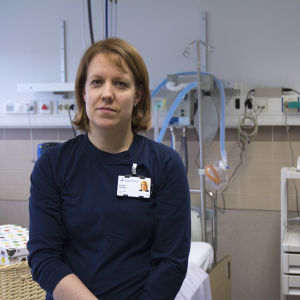 En kvinna som arbetar som barnmorska. Sitter på en säng i en förlossningssal.