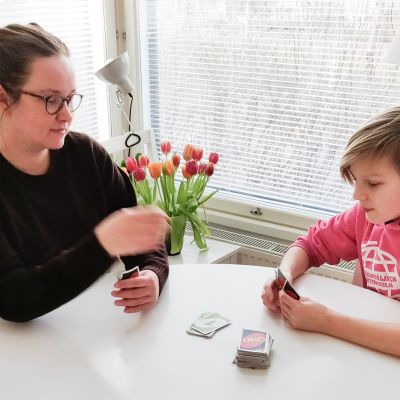 Katrianna Raunio pelaa karanteenissa olevan poikansa kanssa korttia pöydän ääressä.