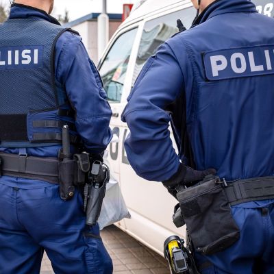 Kaksi järjestyspoliisia takaapäin kuvattuna.
