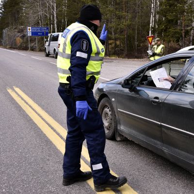 Kuvassa poliisi tarkastaa autoilijaa tiellä.