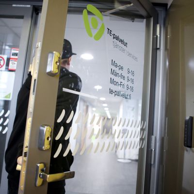 Mies astuu sisään työvoimatoimiston ovesta.