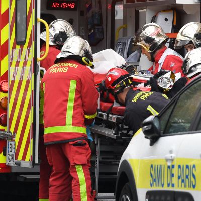 Palomiehet siirtävät puukotuksessa loukkaantunutta ambulanssiin Pariisissa.