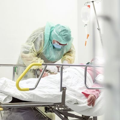 Suojavarustukseen pukeutunut hoitaja ottaa näytettä koronapotilaiden hoitoon tarkoitetulla osastolla Turun yliopistollisessa keskussairaalassa.