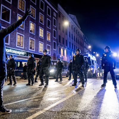 Protestoija seisoo poliisien edessä.