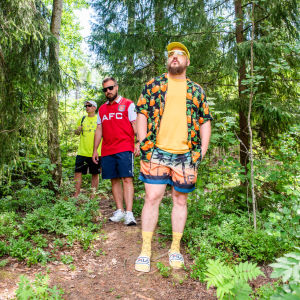 Rap-ryhmä Teflon Brothers kävelee metsäpolulla kesävaatteissa.
