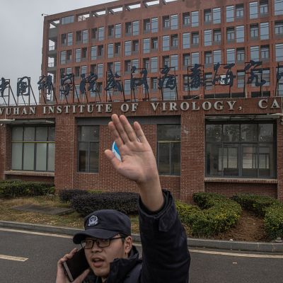 Vartija yrittää estää valokuvaajaa ottamasta kuvia Wuhanin virologian instituutin edessä.