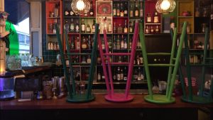 Kunderna får komma tillbaka efter den 3.1, men många krögare tror restriktionerna kanske förlängs. Färggranna barstolar har radats upp och ner på bardisken i en stängd restaurang.