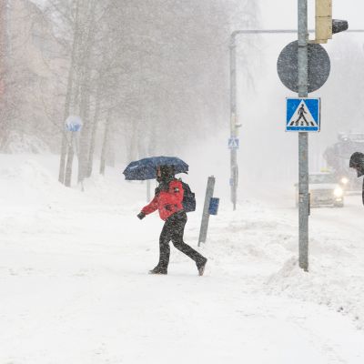 Ihmiset kävelevät lumimyräkässä.