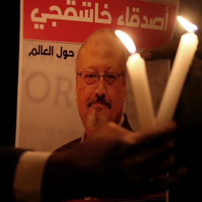 Mielenosoittaja kantaa Jamal Khashoggin kuvaa ja kahta palavaa kynttilää Saudi-Arabian konsulaatin edessä Istanbulissa, Turkissa.