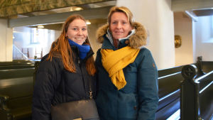 Gitte Brys och Christine Peirsman besökte Borgå domkyrka på onsdagsförmiddagen. En yngre och en äldre kvinna i vinterkläder står inne i en kyrka. De tittar båda in i kameran och ler.
