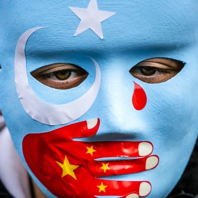 Naamari, jonka suuaukkoa peittämään on maalattu käsi Kiinan lipun väreissä.