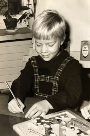 Anna-Maja Henriksson växte upp med sin mamma och sex syskon. Anna-Maja Henriksson som barn. Hon sitter och skriver vid ett bord.
