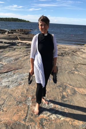 Prästen Patrica Strömbäck vid havet i Pörkenäs. Prästen Patrica Strömbäck med skorna i handen på en klippa vid havet i Pörkenäs.