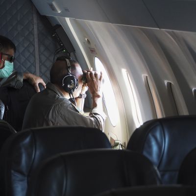 Indonesian laivaston lentokoneen miehistö kiikaroi koneen ikkunasta.