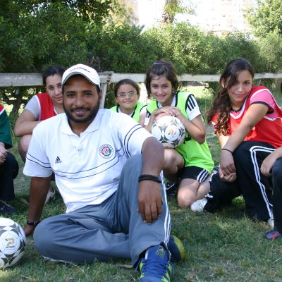 Aleksandrialaisen Sporting-joukkueen tyttöjä futisharjoitusten tauolla valmentajan kanssa.