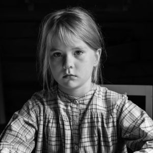 Svartvit närbild på Je'vida (Agafia Niemenmaa) som allvarsamt ser rakt in i kameran.