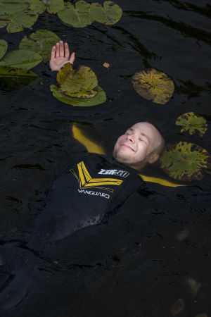 Juha Riikonen kelluu märkäpuku päällä vedessä lumpeiden seassa.