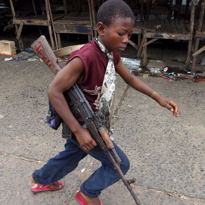 Mannen ska ha haft en ledande position inom rebellgruppen RUF. De är bland annat ökända för att ha använt sig av barnsoldater. Bilden är tagen i Liberia år 2003. Barnsoldar med ett vapen i handen.