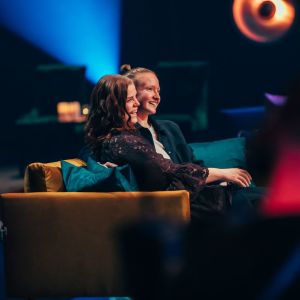 Pariskunta istuu sohvalla kuuntelemassa SuomiLOVE-esitystä