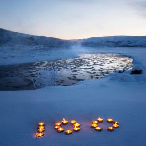 Talvinen jokimaisema, jossa kynttilöistä tehty numero 100.
