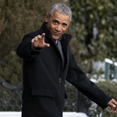 Barack Obama katsoo kameraan ja nostaa kättä tervehdykseksi.