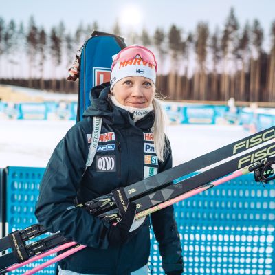 Kaisa Mäkäräinen poseeraa kameralle sukset kädessään.