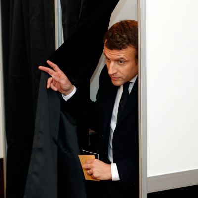 Macron tulee verhon takaa äänestyskopista.