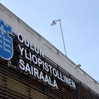 Oulun yliopistollisen sairaalan kyltti sairaalarakennuksen seinässä.