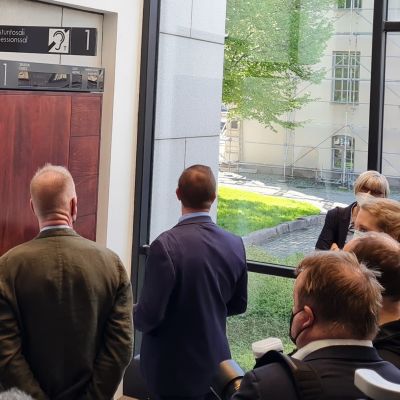 Den åtalade står utanför rättssalen omringad av media.