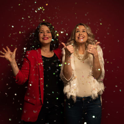 Två leende kvinnor i konfettiregn