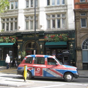 Brittilipun kuosissa oleva taksi pubin edessä Lontoossa.