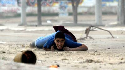 Ung palestinier tar skydd under strider i Gaza.