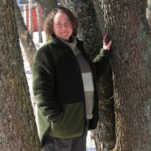 Dosentti Kirsi Lehdon mukaan me kaikki kannamme muistoja elämän synnystä kehossamme. Nainen seisoo kevättalvella auringonpaisteessa puiden välissä.