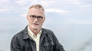 Henrik meinander guidar tittarna i serien Tolv ting om Finland. Henrik Meinander står på ett Sverigebåtdens däck.