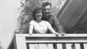 Erik Jahns mamma Margit och eventuellt Eriks biologiska pappa en sommardag 1956 i Hangö En gammal svartvit bild av en kvinna och en man som står nära varandra på en balkong och tittar in i kameran.