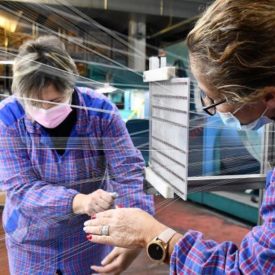 Två personer arbetar med trådar vid en textilfabrik i Italien.