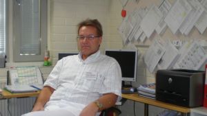 Juhani Salparanta är ledande tandläkare i Jakobstadsregionen, där man just nu söker två nya tandläkare för att kunna ta sig an den långa vårdkön. Mansperson i läkarbeklädnad sitter i kontorsrum.